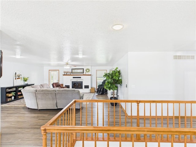 529 SE Dd Hwy, Warrensburg, MO 64093 - living area with ceiling fan, wood finished floors, a fireplace, and a textured ceiling