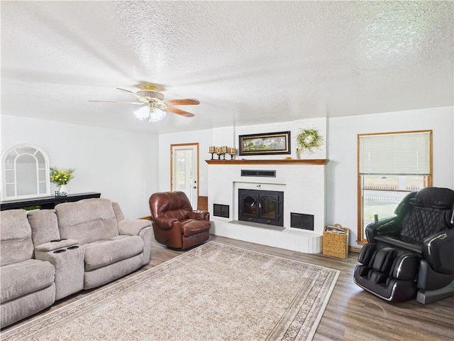 529 SE Dd Hwy, Warrensburg, MO 64093 - living room featuring wood finished floors, a fireplace with raised hearth, a textured ceiling, and ceiling fan