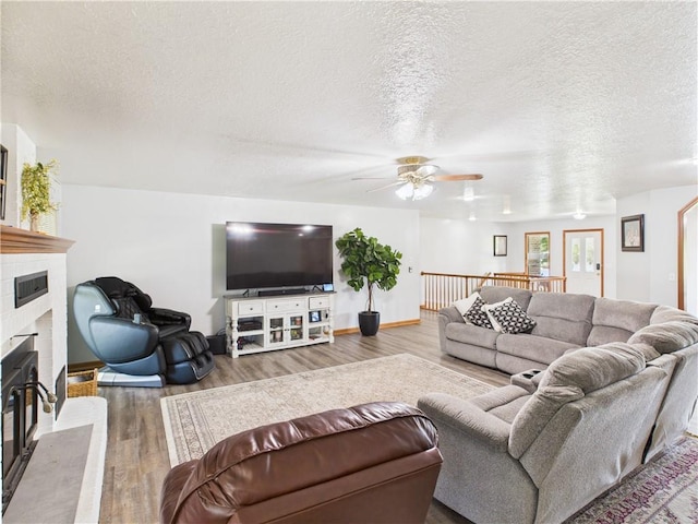 529 SE Dd Hwy, Warrensburg, MO 64093 - living area featuring wood finished floors, a glass covered fireplace, a ceiling fan, and a textured ceiling