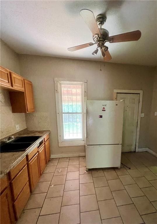 707 Georgia Ave, Kansas City, KS 66101 - kitchen with freestanding refrigerator, light tile patterned floors, ceiling fan, brown cabinetry, and light countertops