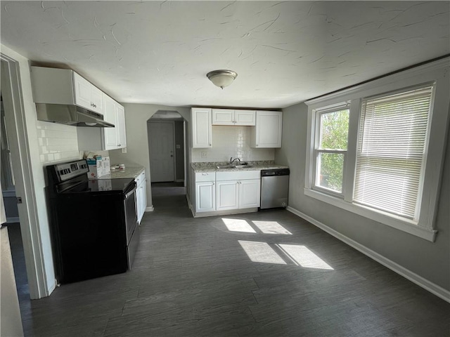 13508 E Silver Ln, Independence, MO 64050 - kitchen with stainless steel appliances, under cabinet range hood, arched walkways, and white cabinetry