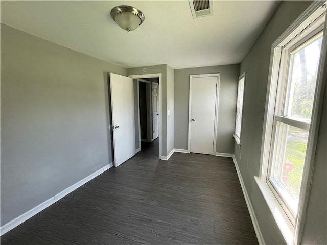 13508 E Silver Ln, Independence, MO 64050 - unfurnished bedroom featuring multiple windows and dark wood finished floors