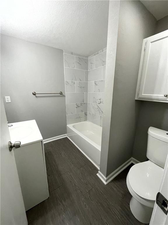 13508 E Silver Ln, Independence, MO 64050 - full bath with vanity, wood finished floors, a textured ceiling, and shower / washtub combination