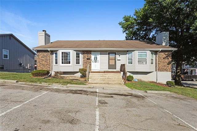 14011 Dunbar Ct, Grandview, MO 64030 - view of front of home with a chimney, uncovered parking, and brick siding