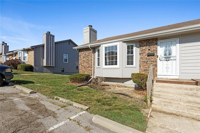 14011 Dunbar Ct, Grandview, MO 64030 - view of front facade featuring a front yard, brick siding, and a chimney