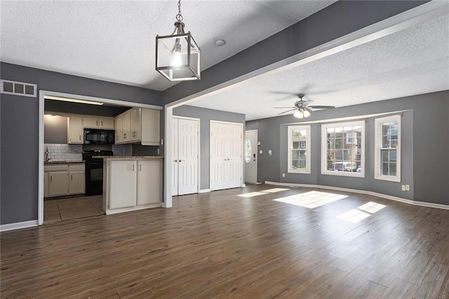 14011 Dunbar Ct, Grandview, MO 64030 - unfurnished living room with dark wood-style floors, a ceiling fan, and a textured ceiling