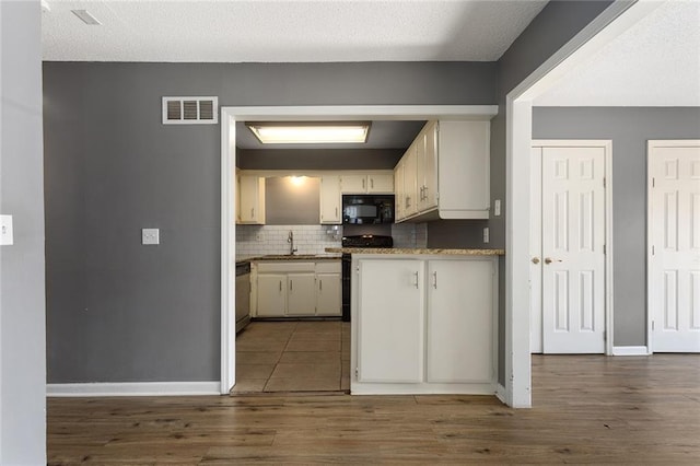 14011 Dunbar Ct, Grandview, MO 64030 - kitchen with black microwave, decorative backsplash, stainless steel dishwasher, wood finished floors, and range