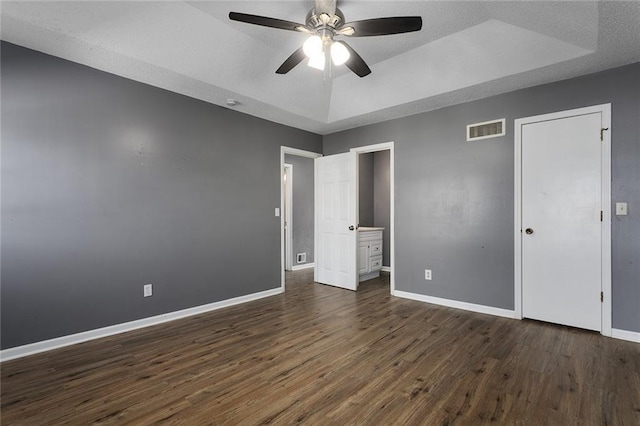 14011 Dunbar Ct, Grandview, MO 64030 - unfurnished bedroom featuring a raised ceiling, dark wood-style floors, and a ceiling fan