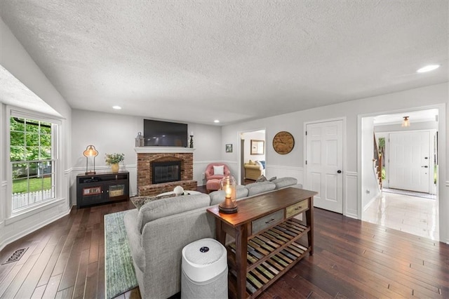 6710 Broadmoor St, Overland Park, KS 66204 - living area with a textured ceiling, dark wood-style floors, a brick fireplace, recessed lighting, and wainscoting