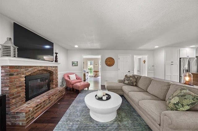 6710 Broadmoor St, Overland Park, KS 66204 - living area featuring dark wood-type flooring, a brick fireplace, a textured ceiling, wainscoting, and recessed lighting
