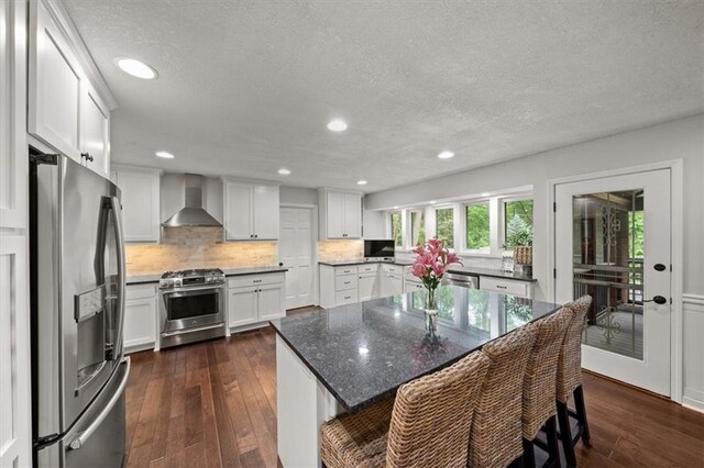 6710 Broadmoor St, Overland Park, KS 66204 - kitchen featuring appliances with stainless steel finishes, wall chimney range hood, dark wood finished floors, a textured ceiling, and decorative backsplash