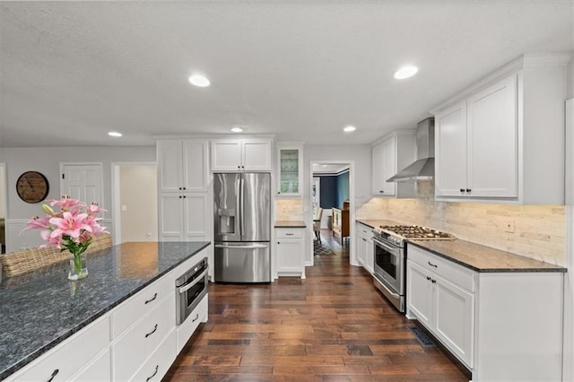 6710 Broadmoor St, Overland Park, KS 66204 - kitchen featuring wall chimney range hood, appliances with stainless steel finishes, dark wood-type flooring, white cabinetry, and dark stone countertops