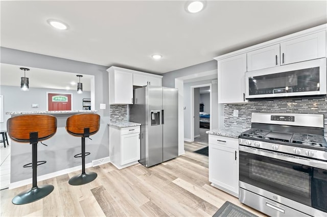 5510 Lafayette Ave, Kansas City, KS 66104 - kitchen featuring stainless steel appliances, white cabinetry, tasteful backsplash, light wood-style floors, and recessed lighting