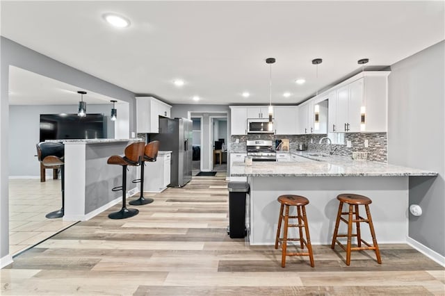 5510 Lafayette Ave, Kansas City, KS 66104 - kitchen with stainless steel appliances, a peninsula, light stone countertops, white cabinetry, and recessed lighting