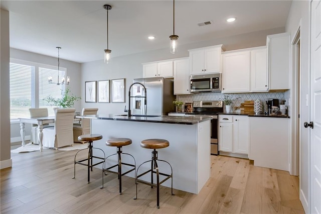 3323 N 109th Ter, Kansas City, KS 66109 - kitchen featuring stainless steel appliances, dark countertops, tasteful backsplash, a kitchen breakfast bar, and light wood finished floors