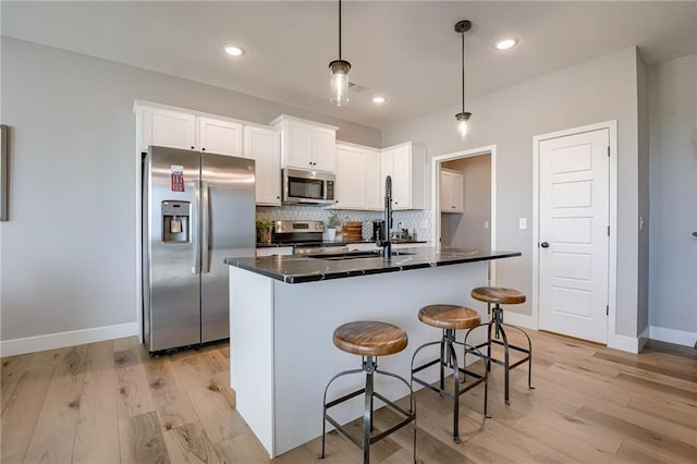 3323 N 109th Ter, Kansas City, KS 66109 - kitchen featuring appliances with stainless steel finishes, dark countertops, decorative backsplash, white cabinetry, and light wood-style floors