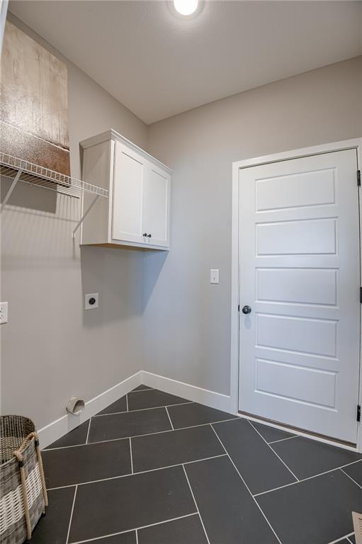 3323 N 109th Ter, Kansas City, KS 66109 - laundry area with electric dryer hookup, dark tile patterned flooring, and cabinet space