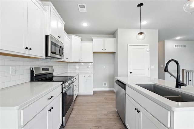 3319 N 109th Ter, Kansas City, KS 66109 - kitchen with appliances with stainless steel finishes, light wood-style floors, hanging light fixtures, recessed lighting, and white cabinetry