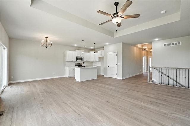 3319 N 109th Ter, Kansas City, KS 66109 - unfurnished living room with a chandelier, a raised ceiling, recessed lighting, a ceiling fan, and light wood-style floors