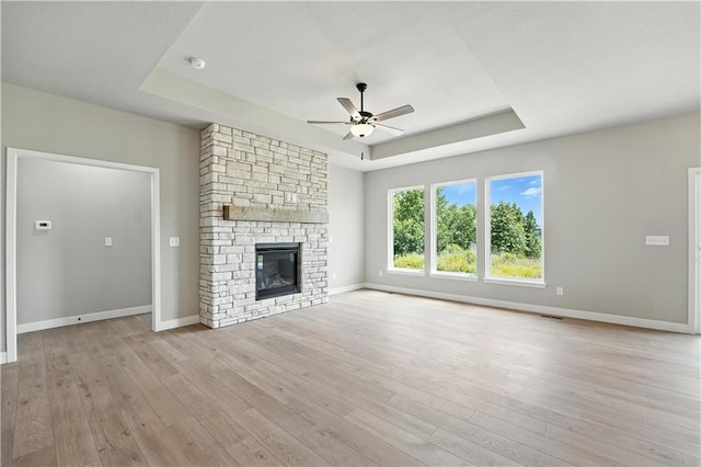 3319 N 109th Ter, Kansas City, KS 66109 - unfurnished living room with a tray ceiling, a ceiling fan, wood-type flooring, and a stone fireplace