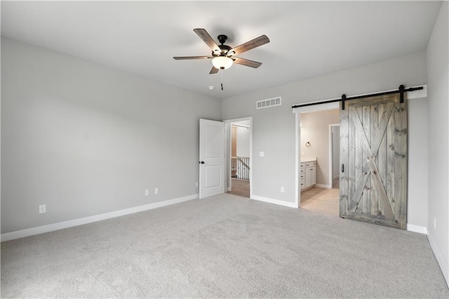 3319 N 109th Ter, Kansas City, KS 66109 - unfurnished bedroom featuring light carpet, connected bathroom, a barn door, and ceiling fan