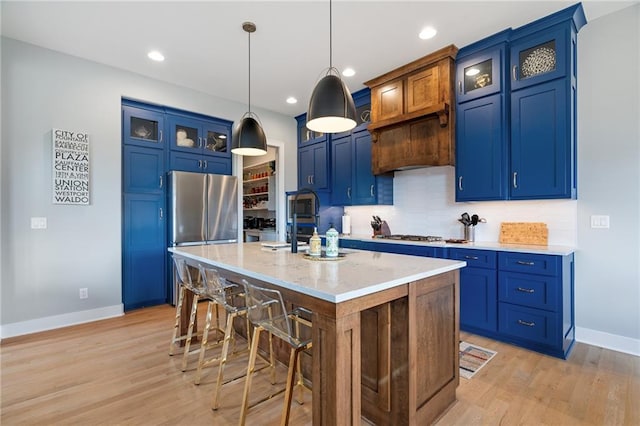 15297 W 172nd Pl, Olathe, KS 66062 - kitchen with blue cabinets, light wood-style floors, a breakfast bar area, appliances with stainless steel finishes, and recessed lighting