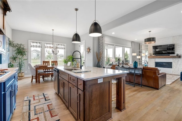 15297 W 172nd Pl, Olathe, KS 66062 - kitchen featuring dishwasher, light countertops, a chandelier, a large fireplace, and light wood-style flooring