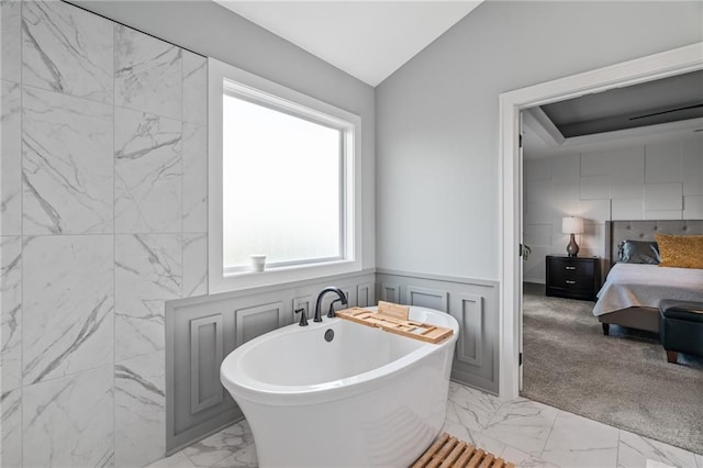 15297 W 172nd Pl, Olathe, KS 66062 - full bathroom featuring marble look tile flooring, a soaking tub, vaulted ceiling, ensuite bathroom, and a wainscoted wall