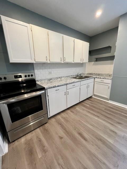 2022 Jules St, Saint Joseph, MO 64501 - kitchen featuring electric range, white cabinetry, open shelves, light wood-style flooring, and light stone counters
