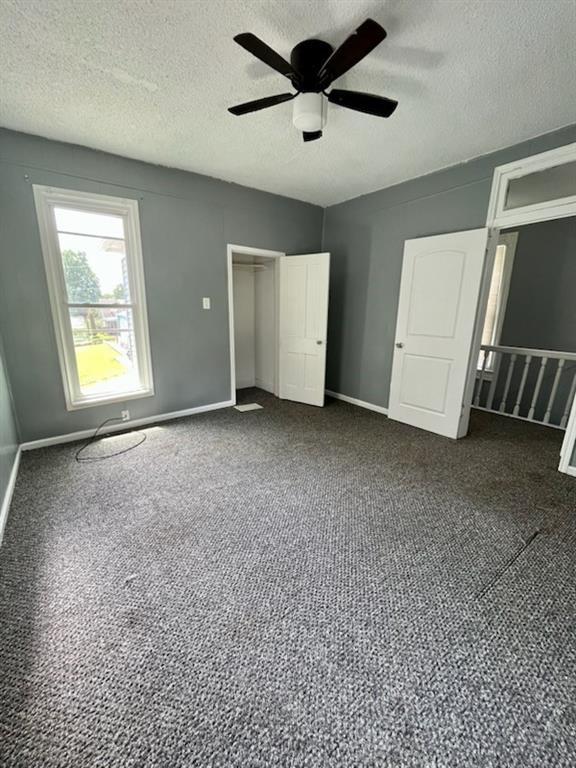2022 Jules St, Saint Joseph, MO 64501 - unfurnished bedroom with a textured ceiling, dark colored carpet, ceiling fan, and a closet