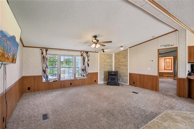 507 NW 165th Rd, Centerview, MO 64019 - unfurnished living room featuring a textured ceiling, a wainscoted wall, wood walls, lofted ceiling, and a wood stove