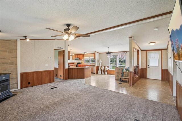 507 NW 165th Rd, Centerview, MO 64019 - living room featuring a textured ceiling, a wainscoted wall, a wood stove, ceiling fan, and wooden walls