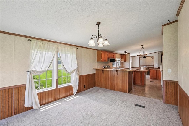 507 NW 165th Rd, Centerview, MO 64019 - kitchen with brown cabinets, a textured ceiling, a peninsula, wainscoting, and a chandelier