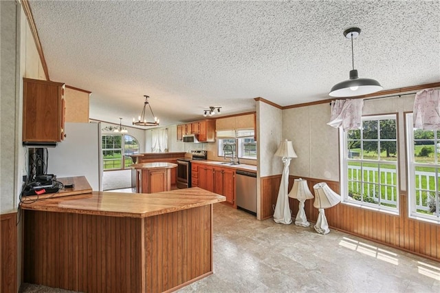 507 NW 165th Rd, Centerview, MO 64019 - kitchen featuring appliances with stainless steel finishes, a textured ceiling, wooden walls, a peninsula, and wainscoting