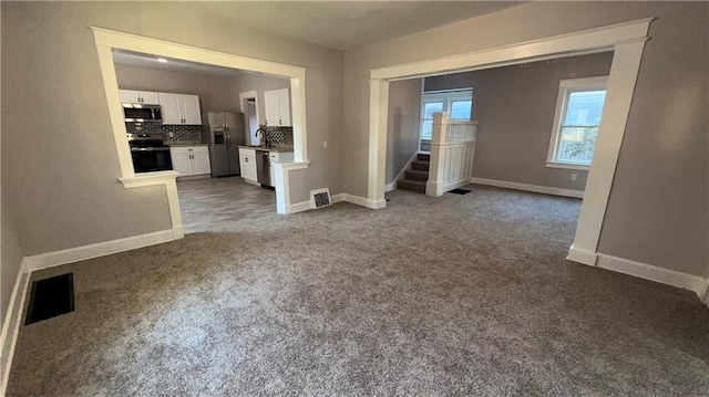1114 N Liberty St, Independence, MO 64050 - unfurnished living room featuring carpet and stairway