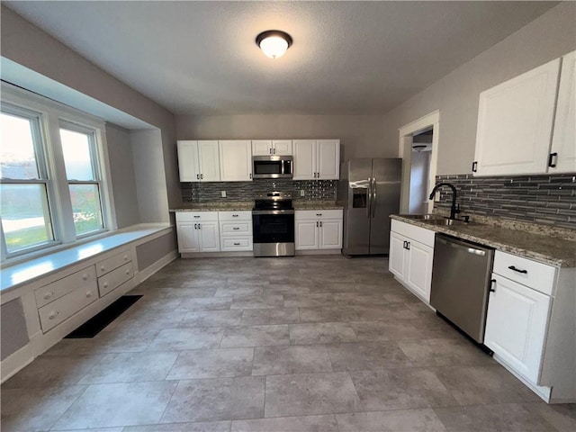 1114 N Liberty St, Independence, MO 64050 - kitchen with appliances with stainless steel finishes, tasteful backsplash, and white cabinetry