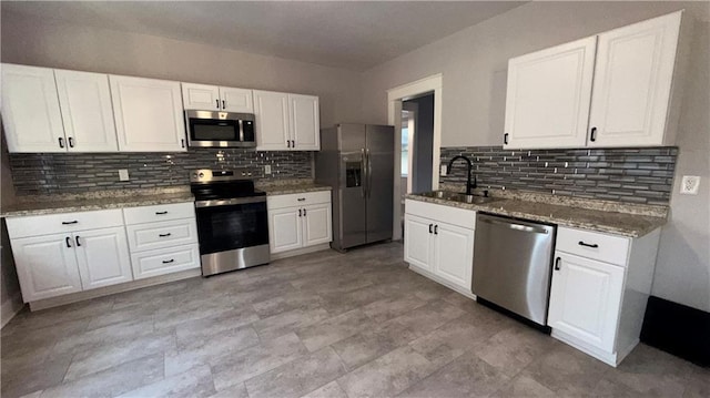 1114 N Liberty St, Independence, MO 64050 - kitchen with appliances with stainless steel finishes, decorative backsplash, and white cabinets