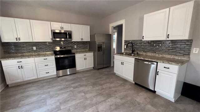 1114 N Liberty St, Independence, MO 64050 - kitchen with appliances with stainless steel finishes, backsplash, and white cabinetry