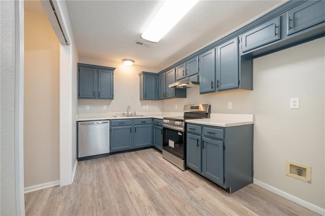 212 NW Parker Dr, Grain Valley, MO 64029 - kitchen with appliances with stainless steel finishes, under cabinet range hood, light wood finished floors, light countertops, and a textured ceiling