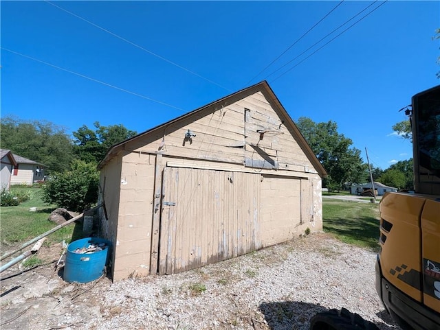 707 N 4th St, La Cygne, KS 66040 - view of side of home featuring an outdoor structure, a detached garage, and concrete block siding