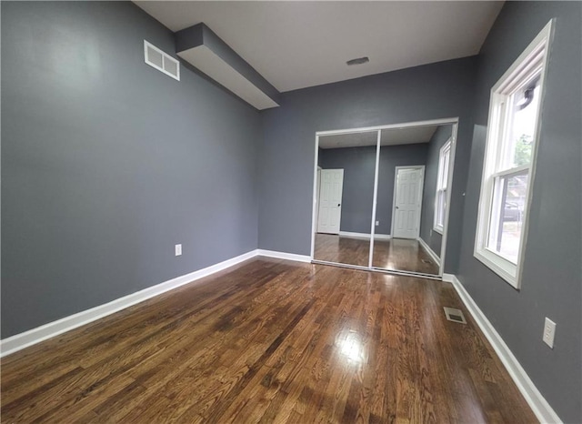 1027 Ohio Ave, Kansas City, KS 66102 - unfurnished bedroom featuring dark wood finished floors, multiple windows, and a closet