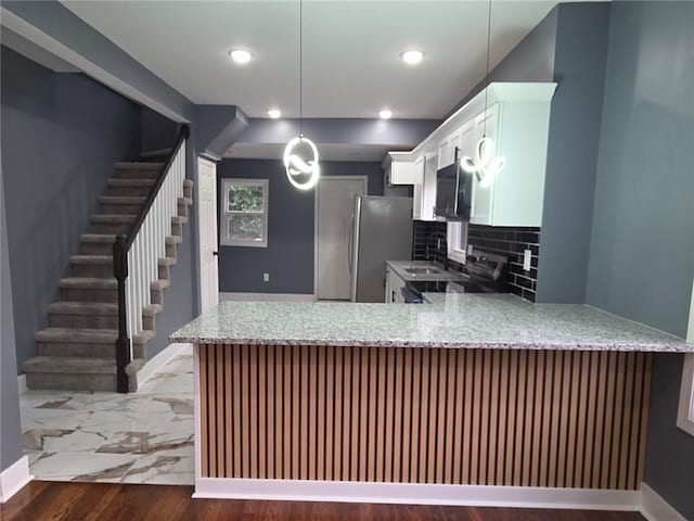 1027 Ohio Ave, Kansas City, KS 66102 - kitchen with a peninsula, light stone countertops, stainless steel electric stove, white cabinets, and backsplash