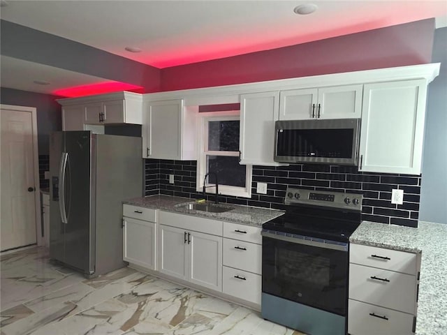 1027 Ohio Ave, Kansas City, KS 66102 - kitchen with appliances with stainless steel finishes, light stone counters, light marble finish flooring, backsplash, and white cabinetry