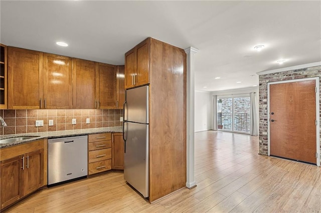5006 Baltimore Ave Unit 205, Kansas City, MO 64112 - kitchen featuring stainless steel appliances, brown cabinetry, light wood-style floors, dark stone counters, and ornamental molding