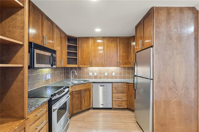 5006 Baltimore Ave Unit 205, Kansas City, MO 64112 - kitchen with stainless steel appliances, open shelves, dark stone countertops, brown cabinetry, and light wood finished floors