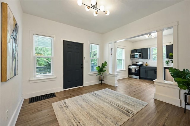 3808 Anderson Ave, Kansas City, MO 64123 - entrance foyer featuring dark wood-style floors, decorative columns, and a chandelier