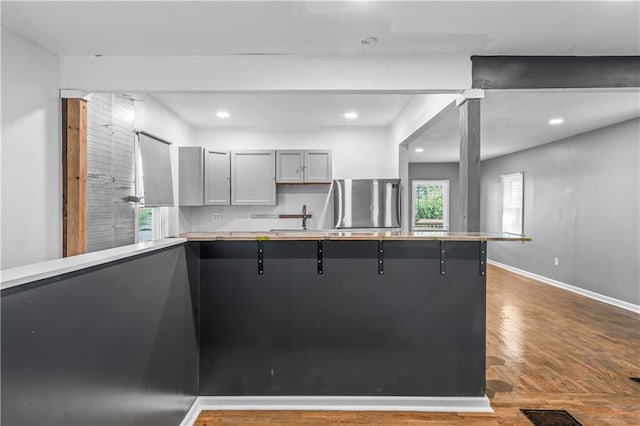 600 Ridgeview Ave, Kansas City, KS 66103 - kitchen with refrigerator, gray cabinets, wood finished floors, a breakfast bar area, and recessed lighting
