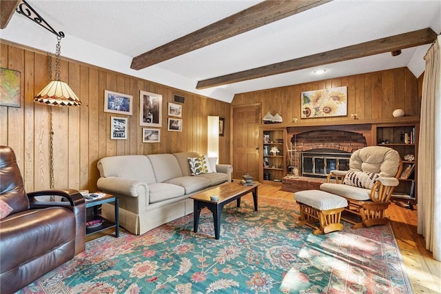 7211 Goodman St, Overland Park, KS 66204 - living room featuring wood finished floors, wood walls, beamed ceiling, and a brick fireplace