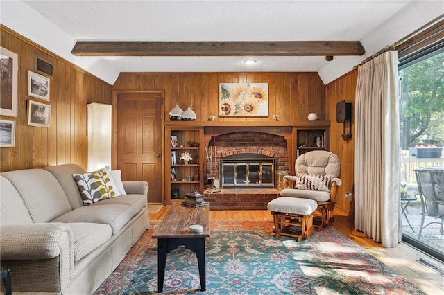7211 Goodman St, Overland Park, KS 66204 - living room with wood walls, wood finished floors, beamed ceiling, and a brick fireplace