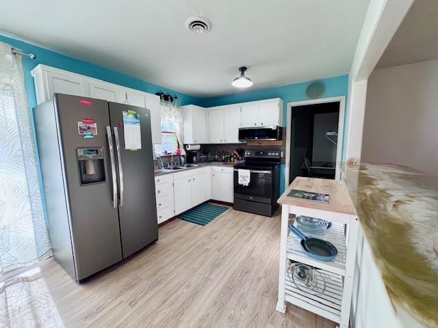 1012 Meadowbrook Rd E, Iola, KS 66749 - kitchen with stainless steel appliances, white cabinetry, and light wood finished floors